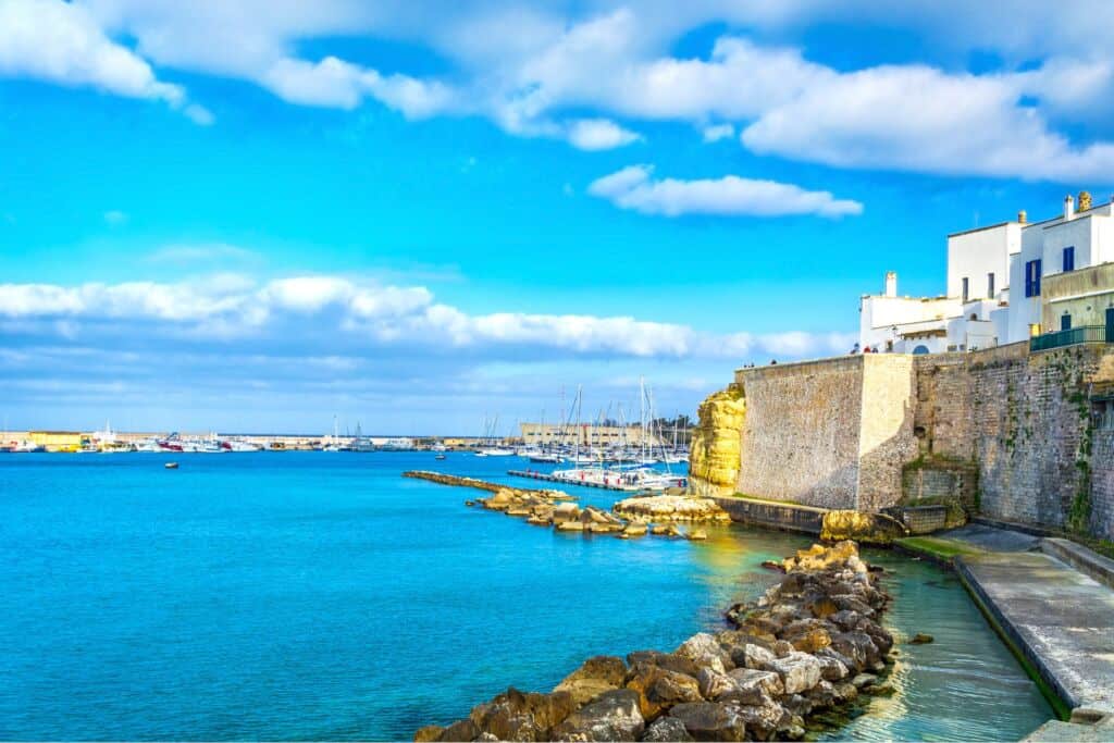 Panorama della costa pugliese con mare cristallino e case bianche.