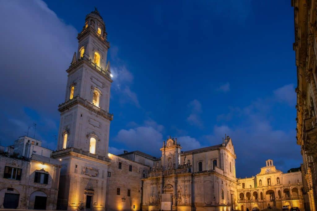 Immagine di un edificio storico illuminato a Lecce, Puglia, durante la sera.