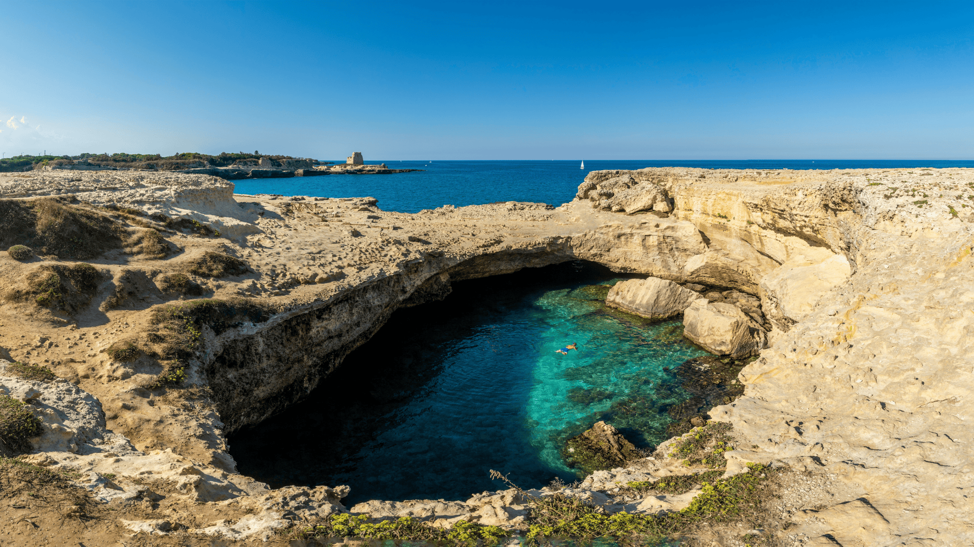 Vista della costa di Puglia con scogliera e mare cristallino.