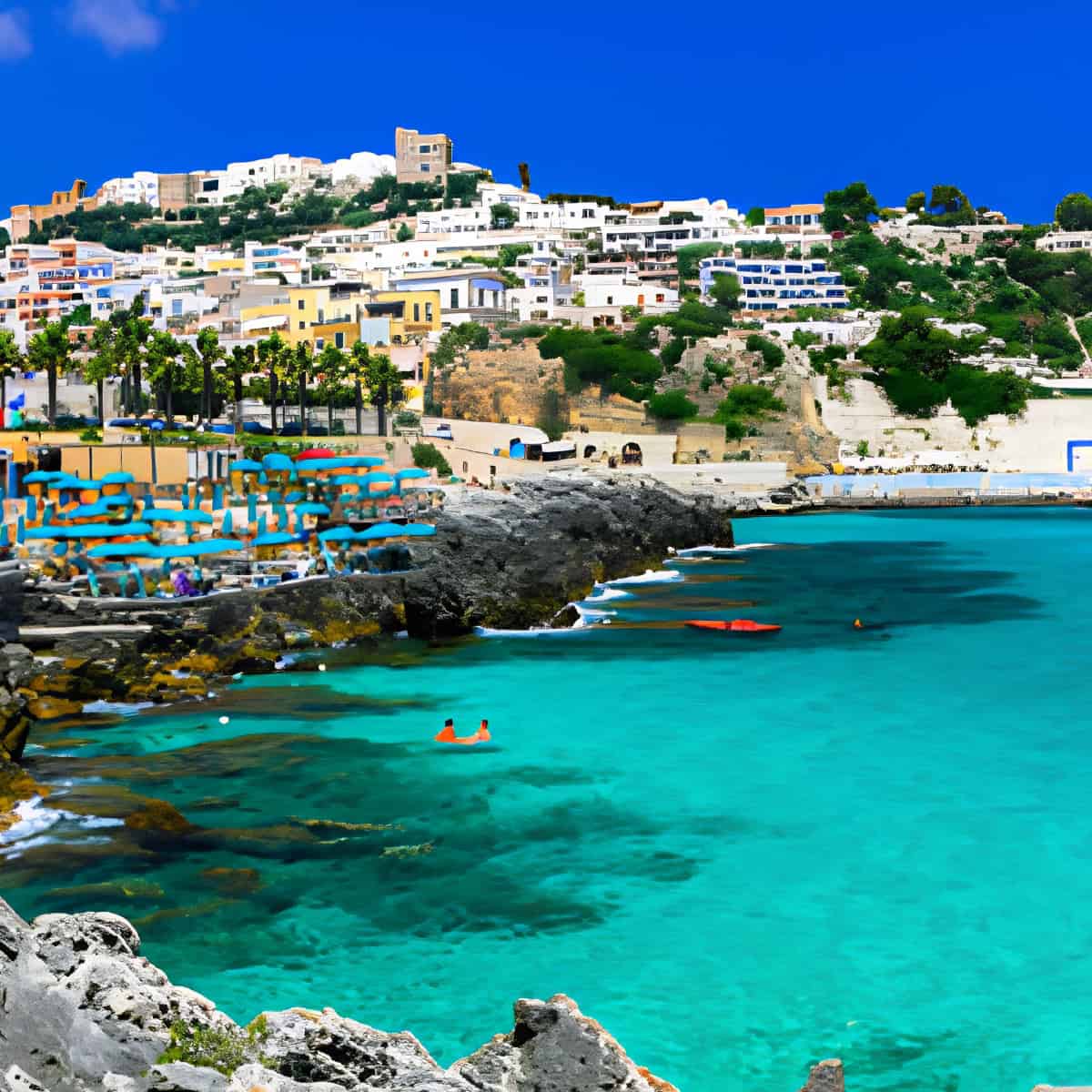 Spiaggia di Puglia con acque cristalline e case bianche sullo sfondo.